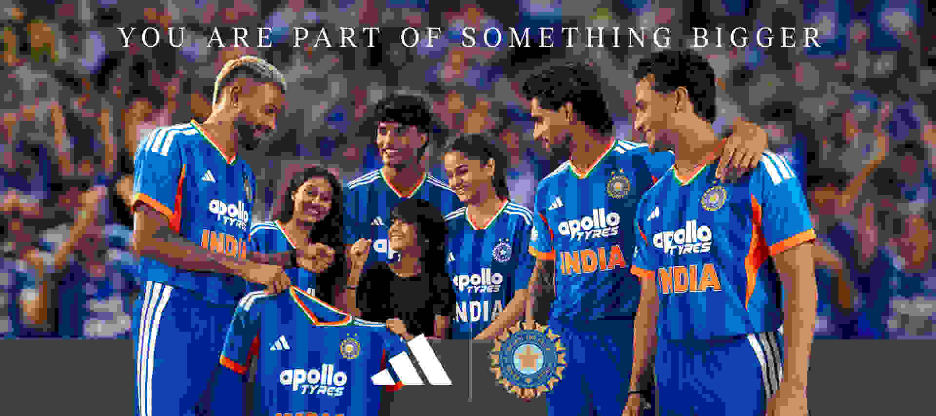 A group of people wearing blue cricket uniforms with the "Apollo Tyres" logo, standing together and embracing, with a large crowd visible in the background.