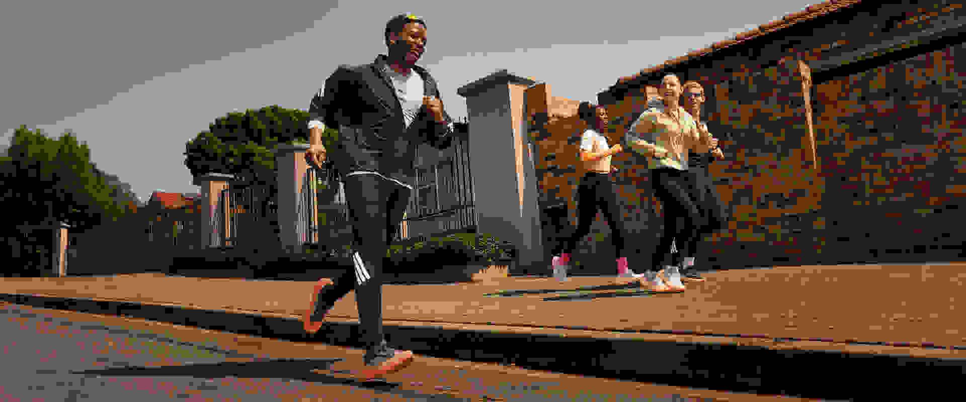 Hình ảnh này cho thấy một nhóm thanh niên đang đứng trên con đường gạch trong một khung cảnh ngoài trời, với các toà nhà và cây xanh có thể nhìn thấy được phía sau.