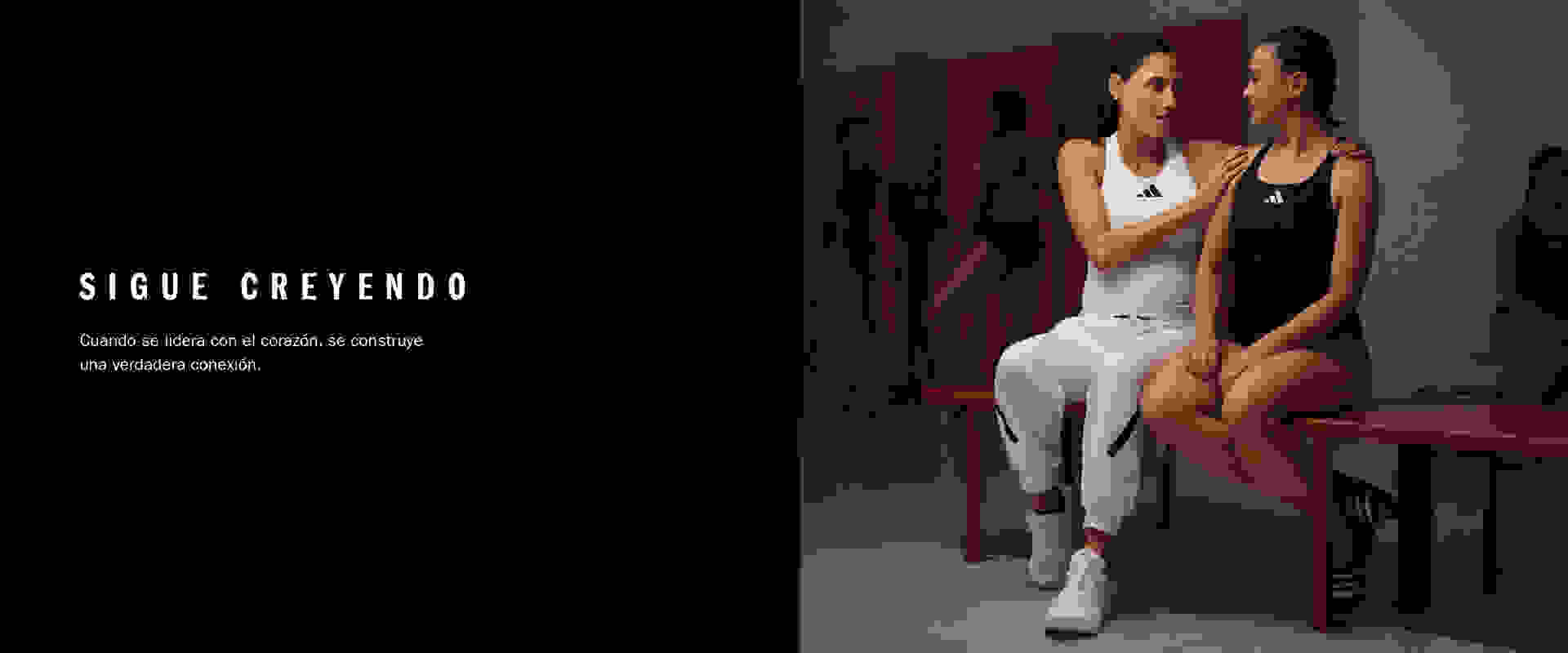 Two women in athletic wear sit together on a bench against a red background.