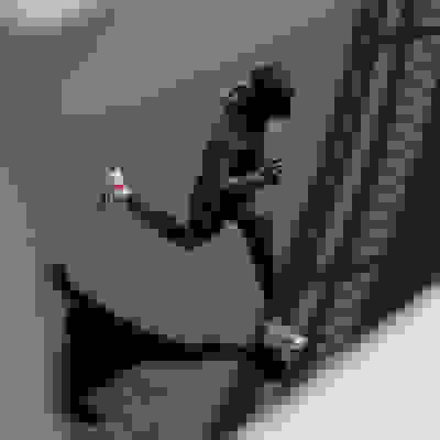 Une personne portant une veste à capuche violette court dans une rue faiblement éclairée, l'ombre projetée sur le sol.