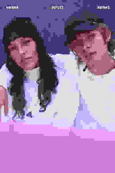 La imagen muestra a dos individuos, una mujer y un hombre, con ropa adidas y posando juntos sobre un fondo morado.