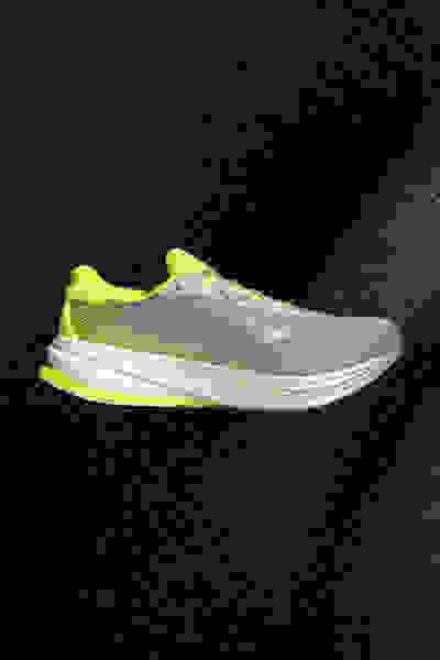 Sneaker sportive in grigio e verde fluo su sfondo scuro.