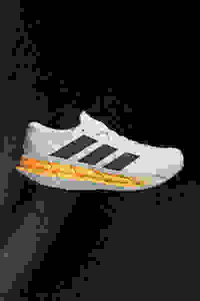 Scarpa da running adidas bianca e arancione su sfondo scuro.