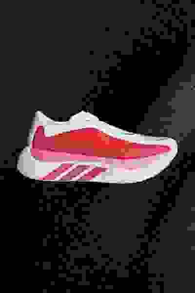 A sleek, red and white athletic shoe stands out against a dark, textured background.