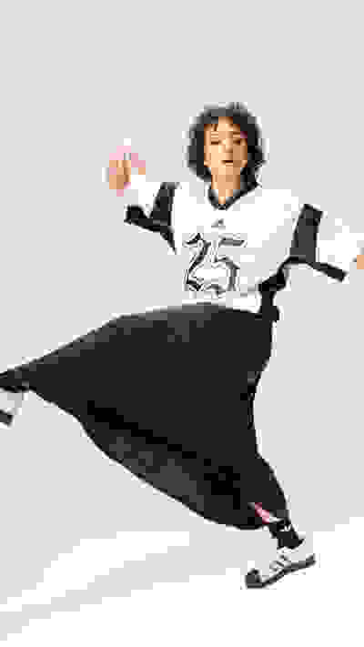 A person wearing a black and white jersey with the number 25 is jumping and gesturing with their hands against a plain white background.