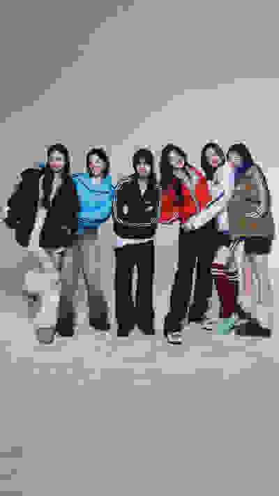 A group of six young women in casual winter attire standing together in a snowy outdoor setting with a clear night sky in the background.