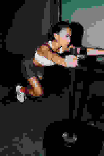 A woman in athletic wear is performing a squat exercise on a weight machine in a dimly lit gym setting.