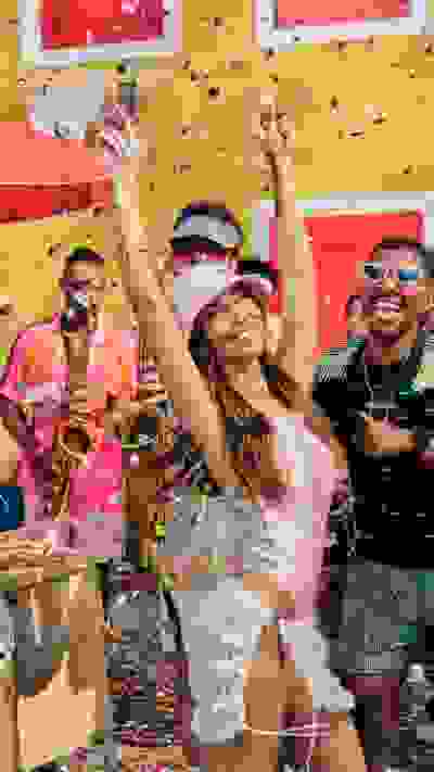 A group of people celebrating enthusiastically, with confetti and musical instruments in a vibrant, colorful setting.