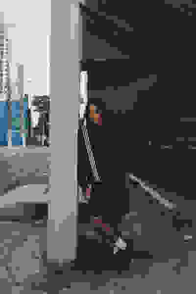 A person wearing a black jacket and shorts is standing under a concrete structure, with tall buildings visible in the background.