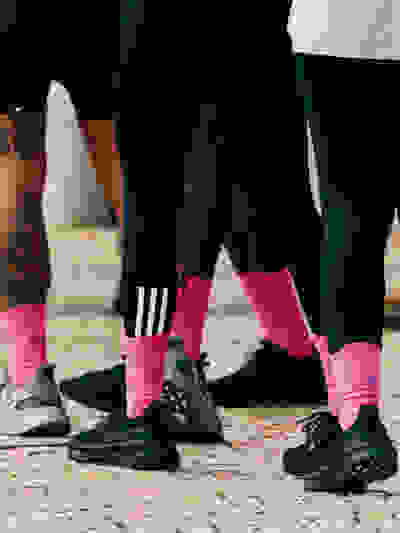 close up of legs of people in black shoes and pink socks