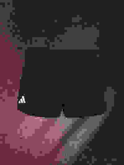 A pair of black athletic shorts with the Adidas logo on a dark, textured background.