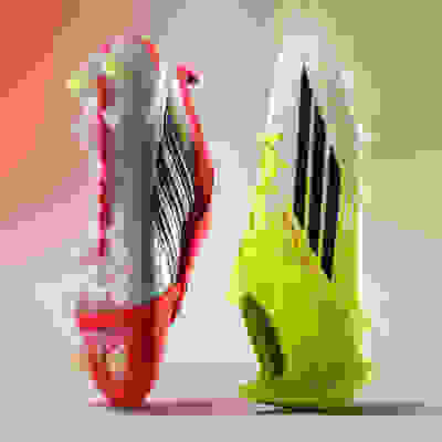 Two vibrant and dynamic soccer cleats in contrasting colors of red and yellow, set against a blurred gradient background.