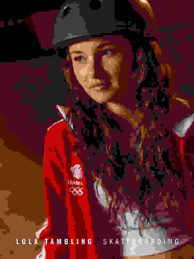The image shows a young woman with curly hair wearing a red jacket with Olympic branding and a protective helmet, suggesting she is a skateboarder.