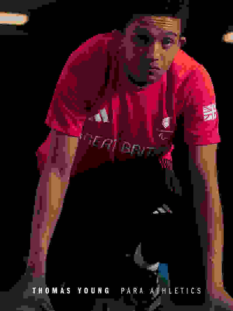 A young man wearing a red "Great Britain" sports jersey stands in a dimly lit setting, his focused expression and athletic build suggesting he is a para-athlete.