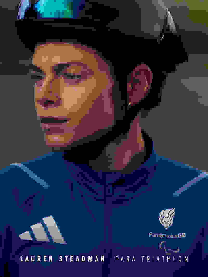 A person wearing a blue sports uniform and a black helmet, with a serious expression on their face, against a dark background.
