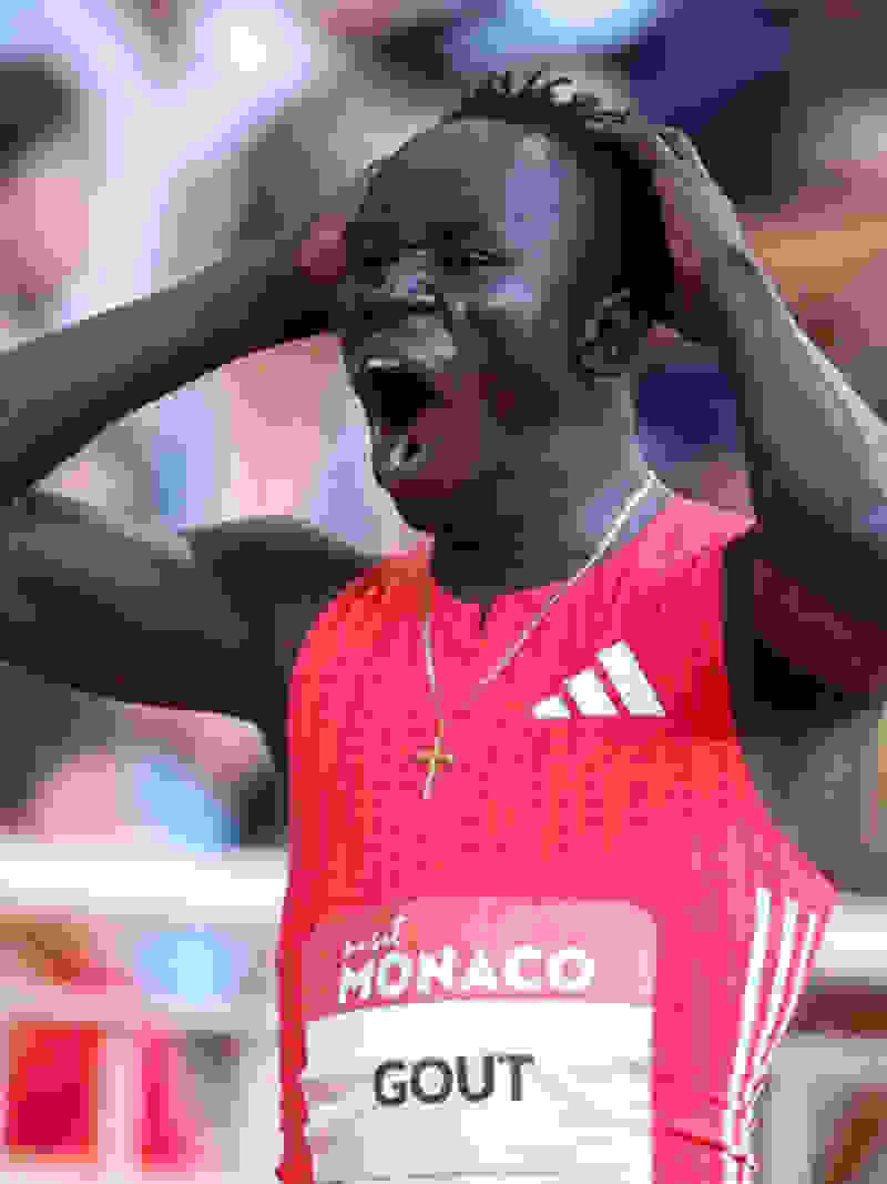 A young man in a red sports jersey with the text "MONACO GOUT" is shown with his hands on his head, appearing to be in a state of distress or excitement.