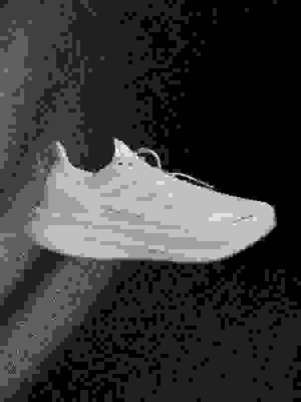 A pair of white and beige athletic shoes is prominently displayed against a dark, textured background.