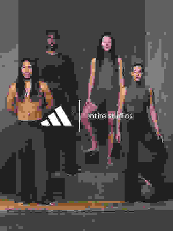 The image features four individuals, three men and one woman, standing together on a wooden platform against a plain background. The individuals are wearing minimal clothing, showcasing their physiques.