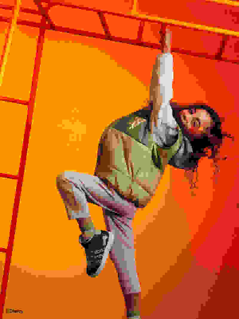 One child swinging from a monkey frame with a Simba shadow beside her, wearing the adidas | Lion King collection