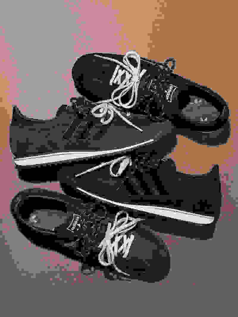 A pair of black and gray sneakers with laces and a beige background.