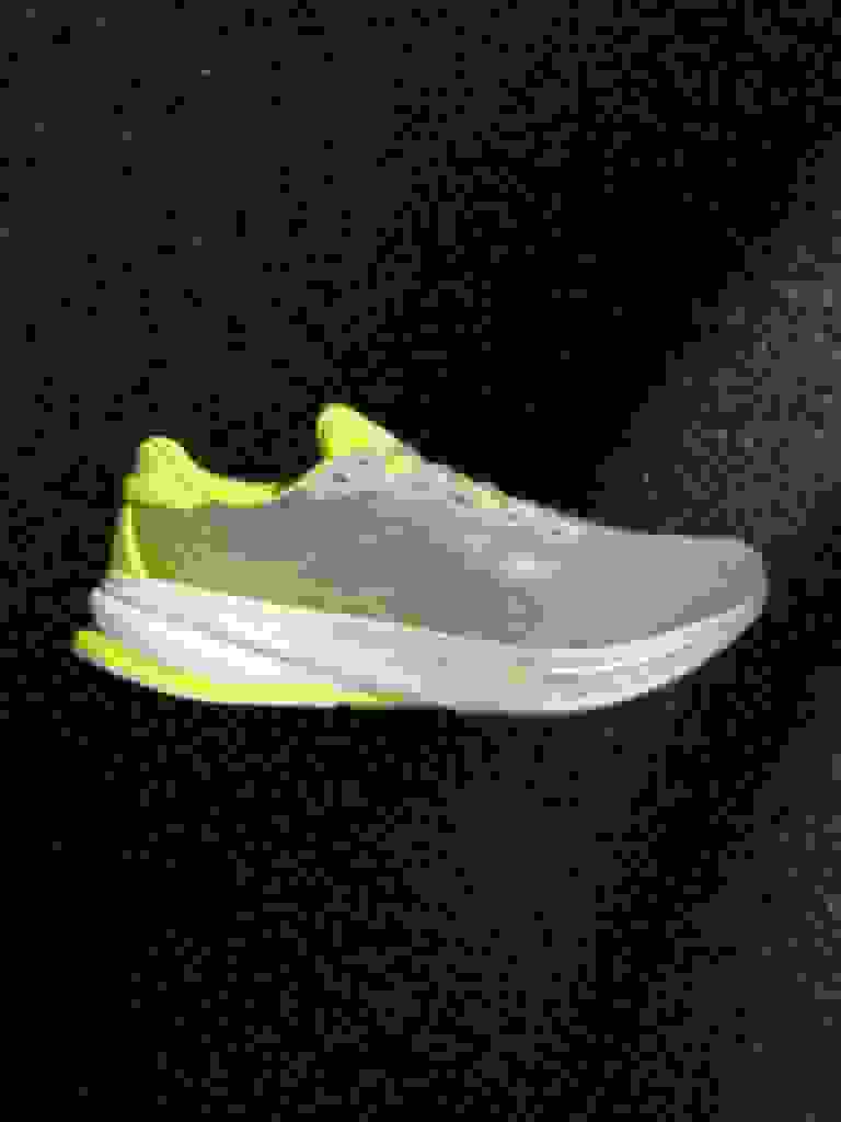A gray and neon yellow athletic shoe against a dark background.