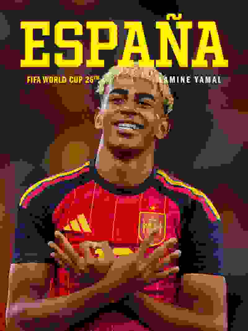 The image shows a smiling soccer player wearing a red and yellow jersey with the word "ESPANA" prominently displayed, standing against a dark background.