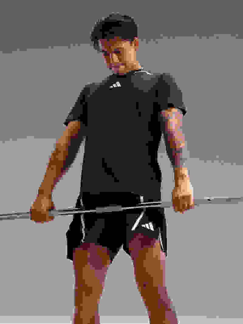 Man wearing adidas training gear performs deadlift.