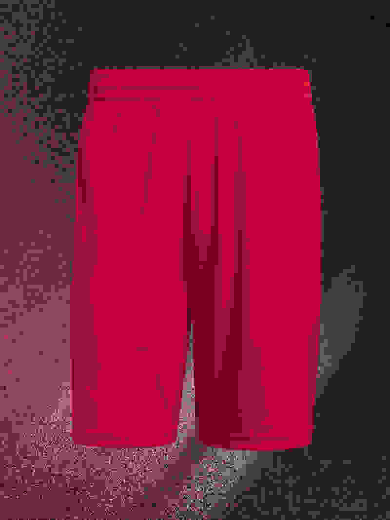 A pair of bright red athletic shorts against a dark, textured background.