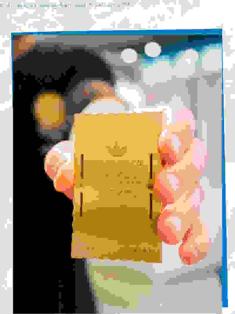 A hand is holding a golden ticket from the movie "Charlie and the Chocolate Factory" against a blurred background.