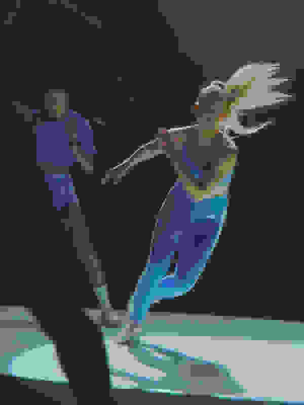 Two people, a man and a woman, are performing a dynamic dance routine on a stage with a dark background.