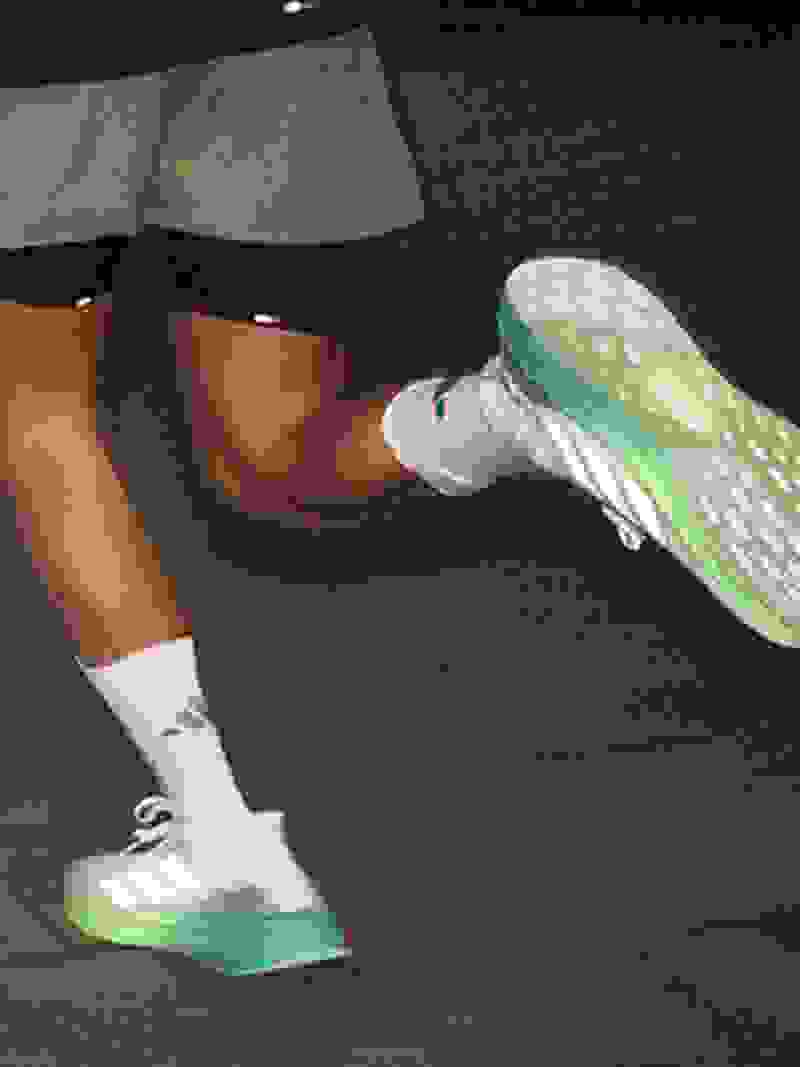 A person in a pink shirt and blue leggings is running on a dirt path surrounded by trees in a natural setting.