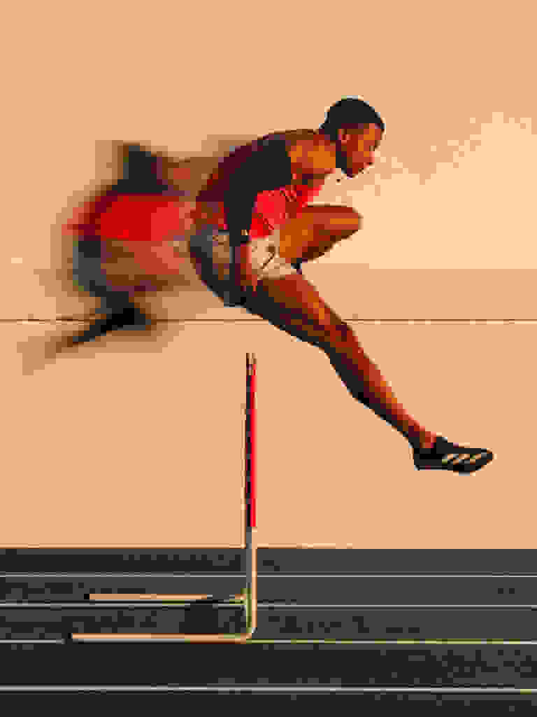 Olympian Sasha Zhoya, jumping over a hurdle, wearing adidas.