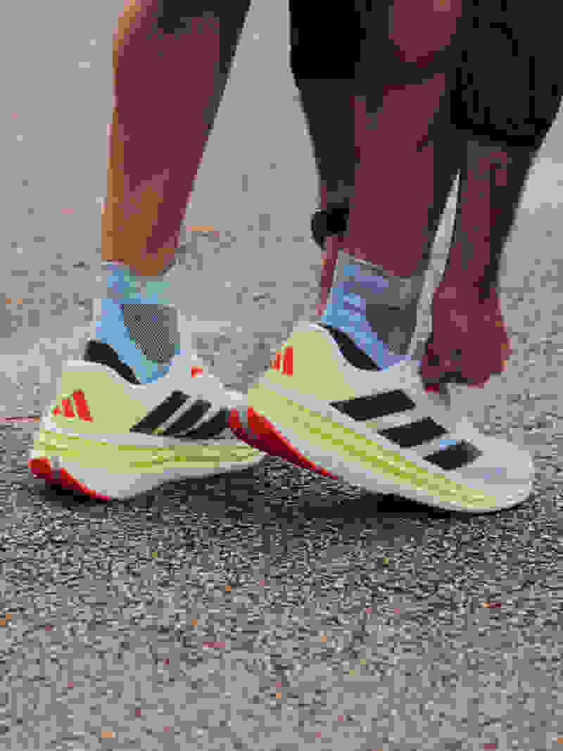 A person in a pink shirt and blue leggings is running on a dirt path surrounded by trees in a natural setting.