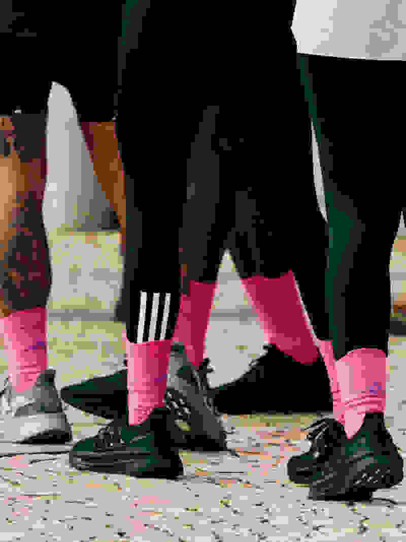 close up of legs of people in black shoes and pink socks