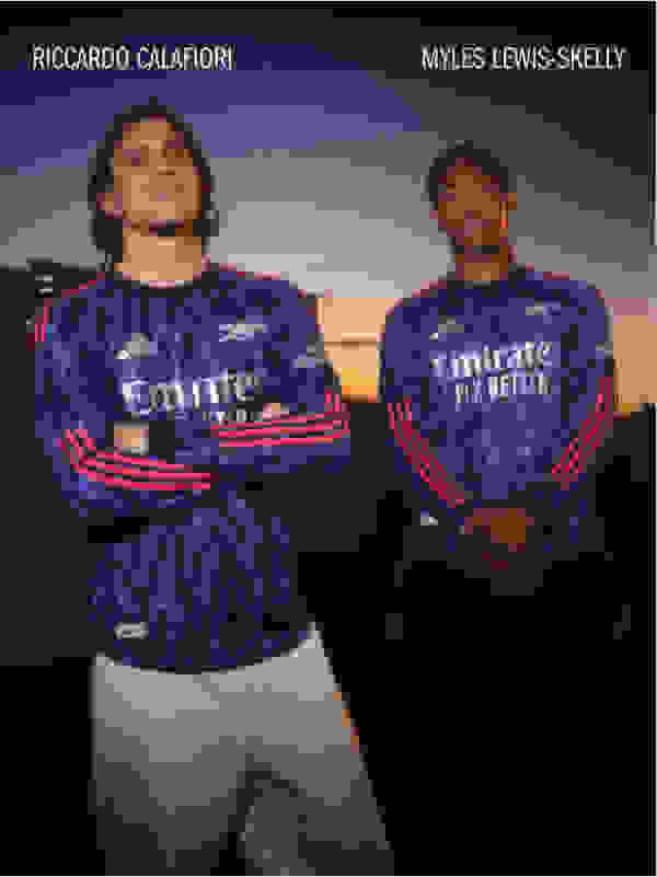 The image shows two soccer players wearing the Arsenal football club's away jersey, posing together in front of a scenic sunset backdrop.