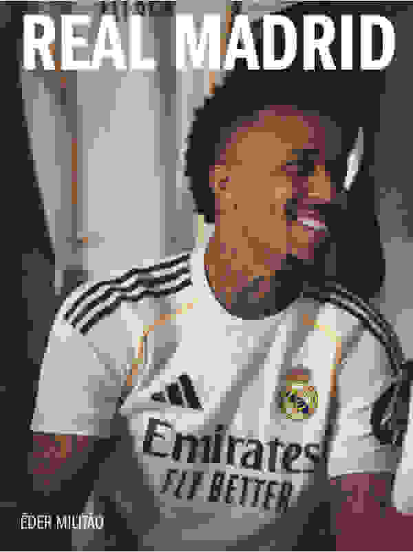 The image shows a smiling man wearing a white Real Madrid soccer jersey with the "Emirates" logo, standing in front of a white background.
