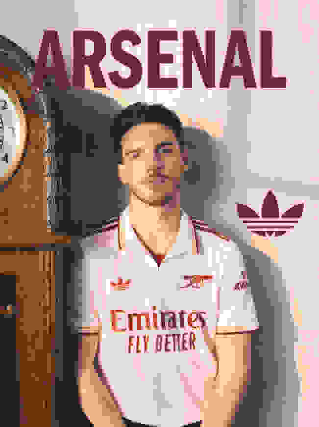 The image features a young man wearing an Arsenal football club jersey, standing in front of a vintage-style clock and the Arsenal logo prominently displayed in the background.