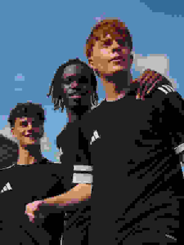 Three footballers standing together on the field.