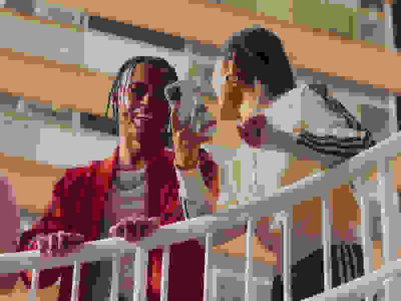 Dos personas recostadas en una barandilla, mirando su teléfono y sonriendo. 