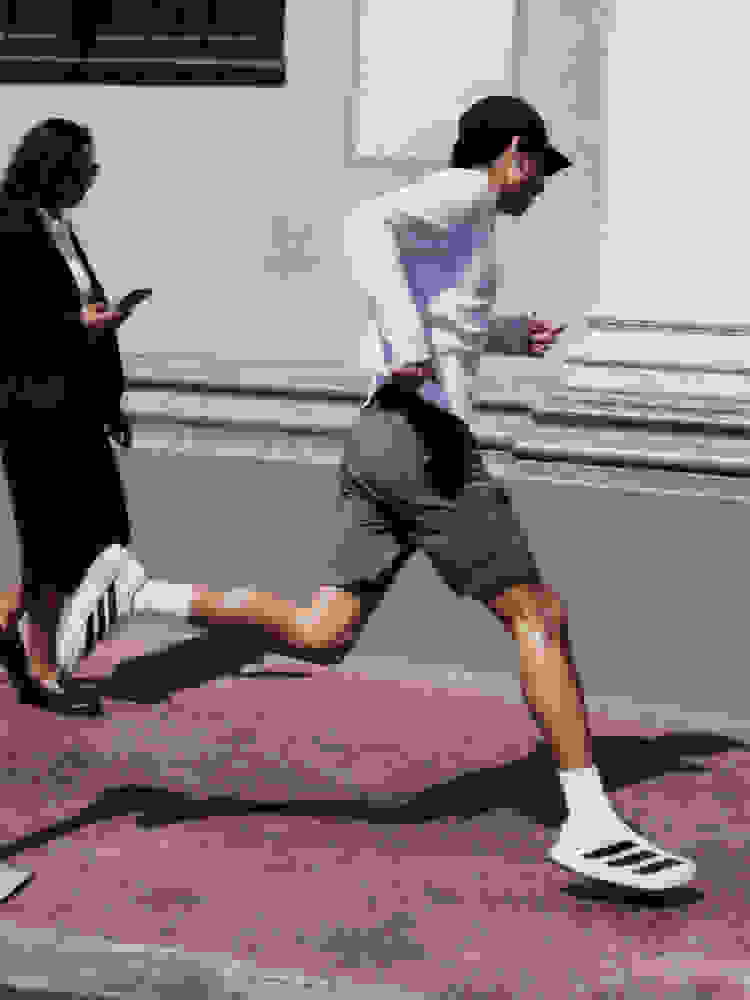 Due persone, una con una camicia bianca e l'altra con una giacca scura, sono coinvolte in quello che sembra essere un alterco fisico su una superficie lastricata di mattoni in un ambiente urbano.