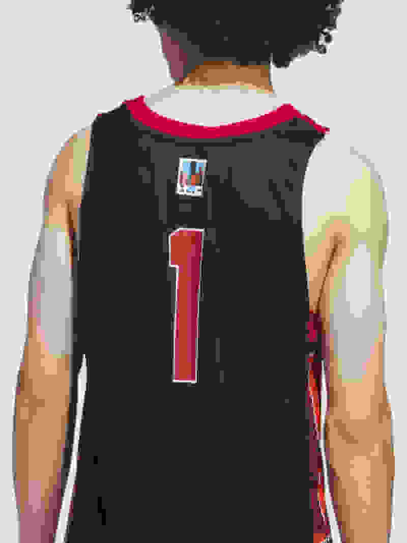 A person wearing a black basketball jersey with the number 1 printed on the back, standing against a plain white background.