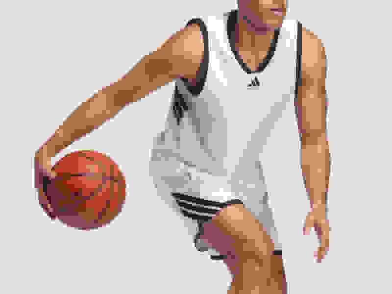 A basketball player in a white jersey is holding a basketball and appears to be in motion on a plain background.