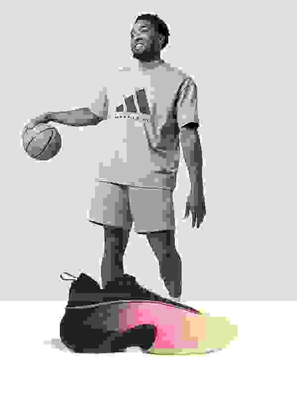 Un homme souriant portant un t-shirt adidas apparaît au premier plan sur une chaussure colorée au look futuriste.