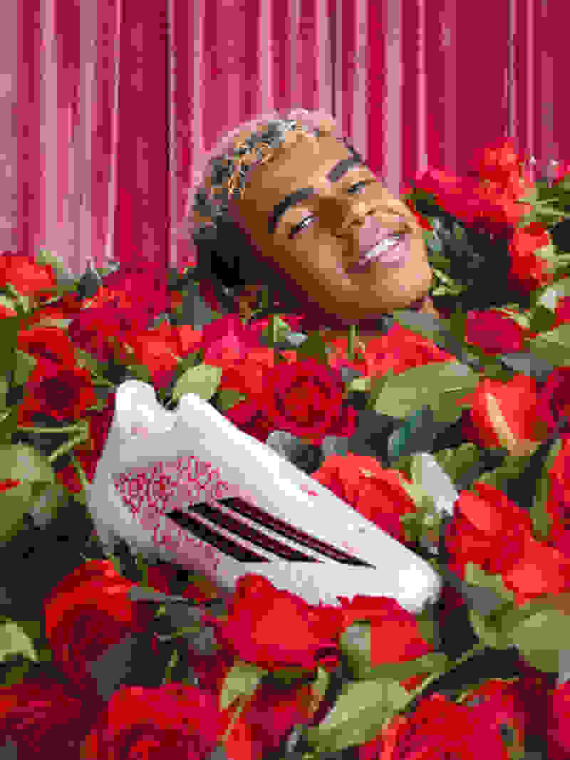 Lamine Yamal Smiles ฝังอยู่ในดอกกุหลาบสีแดง มีเพียง A Head Showing Close His White, Black, And Red adidas F50 Boots