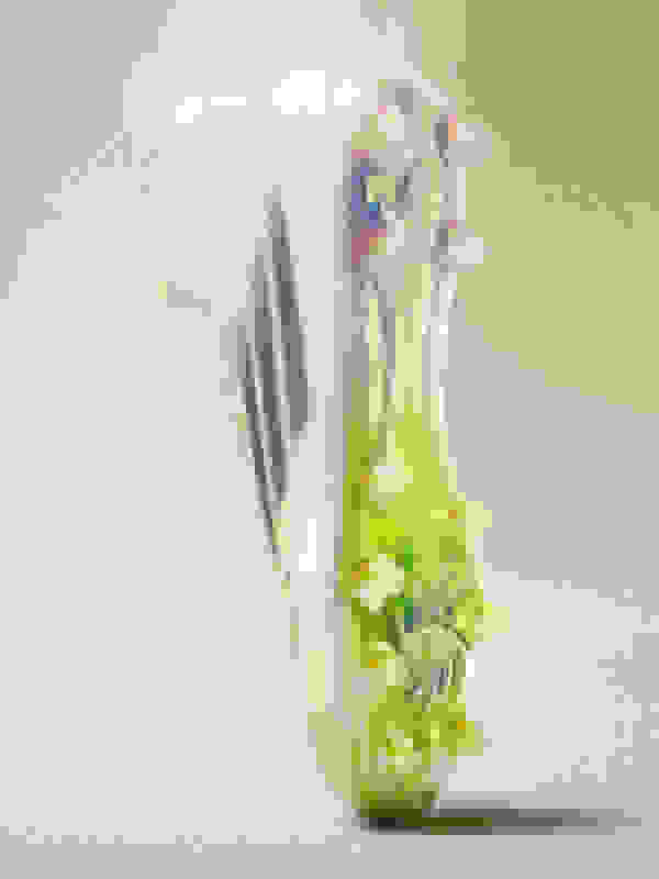 A vibrant, abstract glass sculpture with intricate, swirling patterns and a striking green and yellow color palette, set against a soft, blurred background.