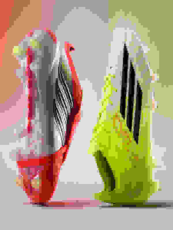 Two colorful and stylized soccer cleats, one in a bright red and white color scheme and the other in a vibrant neon yellow and black design, are the focal point of the image against a soft, blurred background.