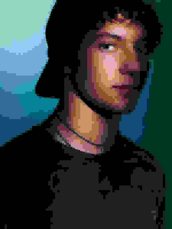 A young man with dark, curly hair and a serious expression, wearing a black shirt with logos, set against a teal-coloured background.