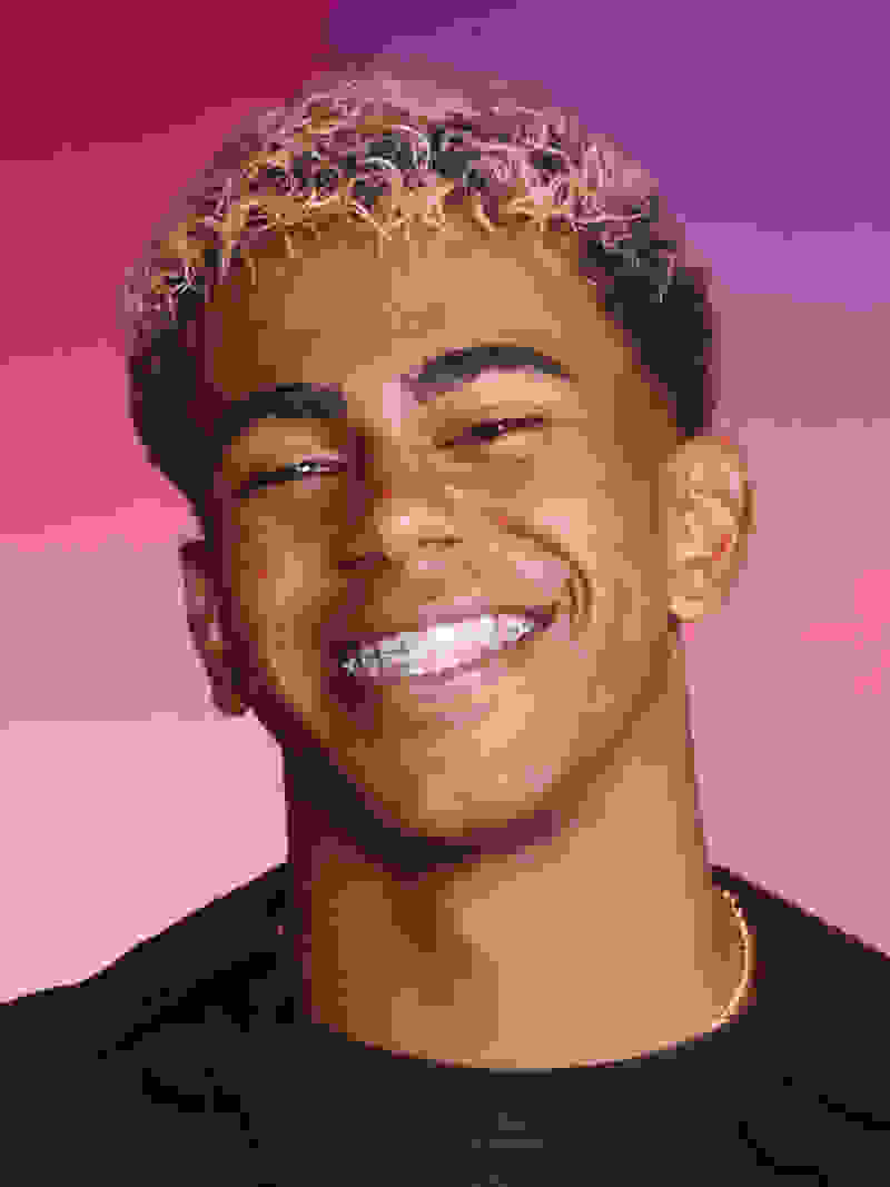 Captura de cabeça de Lamine Yamal a sorrir calorosamente para a câmara, colocada sobre um fundo cor-de-rosa vivo.