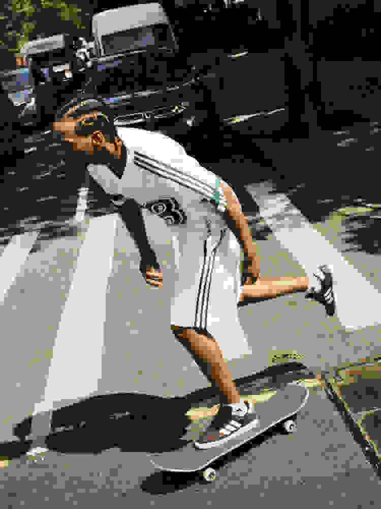 Tyshawn Jones har hvite Tyshawn-plagg med grønne striper, og skater nummer 98 på en crosswalk i brune og hvite adidas Tyshawn II-sko.