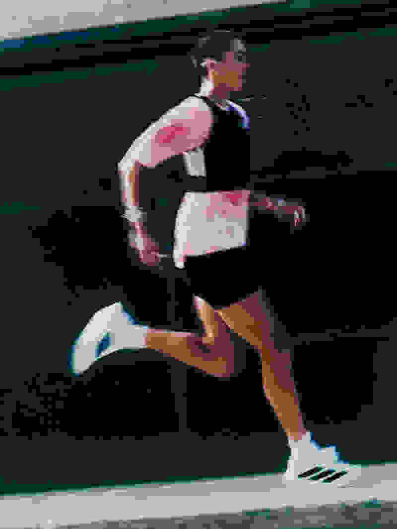 A person in athletic clothing is running on a dark background, with a blurred motion effect creating a sense of movement.